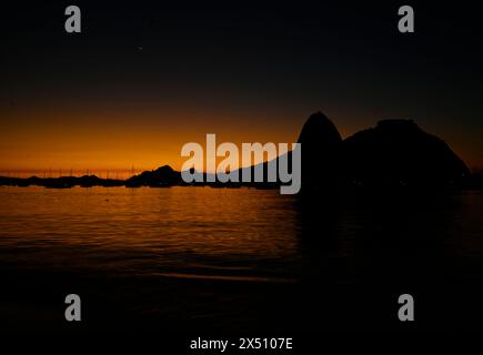 Rio de Janeiro-Brasilien 6. Mai 2024, Sonnenaufgang am Strand Botafogo neben dem Sugarloaf Mountain, traditionelle Postkarte Brasiliens. Rio de Janeiro im Herbst mit Stockfoto