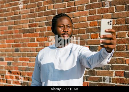 Ein afroamerikaner überprüft das Handy auf der Straße am Sommertag. Millennial Generation und Generation z Menschen. Soziale Netzwerke und Dating-App-Konzept Stockfoto