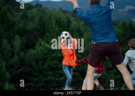 Junge Schüler spielen mit dem Lehrer im Freien, in der Natur, während des Feldunterrichts, laufen mit Ball. Engagierte Lehrer während der Aktivitäten im Freien Stockfoto