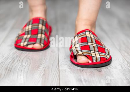 Ein Fuß in einen alten, undichten Slipper. Alter Pantoffel. Sneaker mit Lochmuster. Loch in Hausschuhen. Hochwertige Fotos Stockfoto