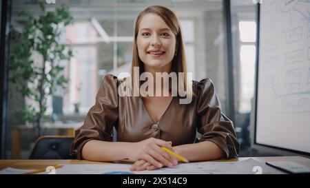 Blickwinkel aus der Kamera mit dem schönen jungen Projektmanager, der ein Videogespräch in einer kreativen Büroumgebung führt. Glückliche kaukasische Spezialistin, die Kollegen über eine Live-Kamera zuhört. Stockfoto