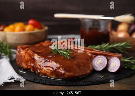 Leckeres mariniertes Fleisch, Rosmarin und Zwiebeln auf Holztisch, Nahaufnahme Stockfoto