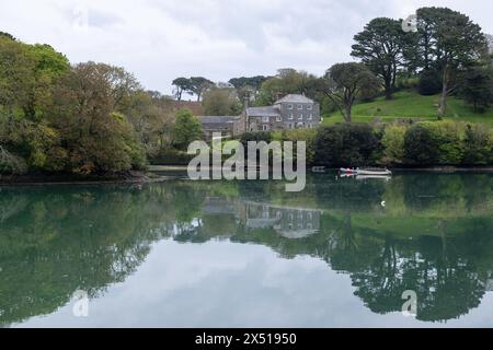 Batson Creek mit spiegelruhigem Wasser, das ein großes Haus am Snapes Point reflektiert, und umliegenden Bäumen - aufgenommen an einem bewölkten Frühlingstag Stockfoto