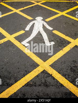 Nahaufnahme eines weiß gemalten Wandermannes in einer gelben Kastenpfanne auf schwarzem Asphalt. Stockfoto