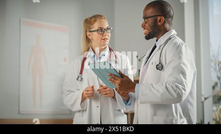Arztpraxis: Schwarzer Arzt spricht mit professioneller Chefschwester, mit Tablet-Computer. Medical Health Care Specialists Diskutieren Testergebnisse, Verschreibungspflichtige Medizin, Patientenbehandlung. Stockfoto