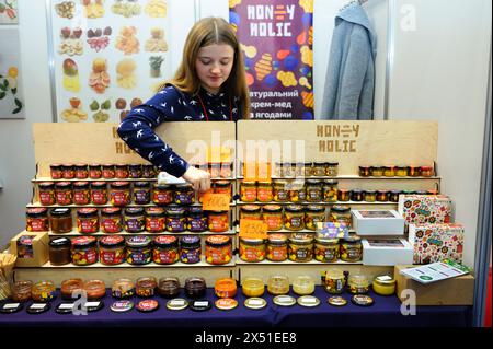 Eine junge Frau, die Honig in Gläsern verkauft, die in Regalen stehen. Januar 2019. Kiew, Ukraine Stockfoto