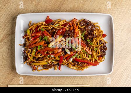 Leckeres asiatisches Rinderbraten mit bunten Gemüse und Nudeln serviert auf einem weißen Teller Stockfoto