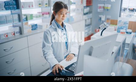 Apotheke Drugstore: Schöne asiatische Apotheker verwendet Kasse Computer, tut Inventar Checkup, Online-Verordnung von Medizin Pakete, Medikamente, Vitaminboxen, Ergänzungen, Gesundheitspflege Produkte Stockfoto