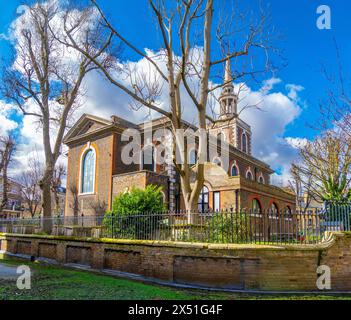 Außenfassade der anglikanischen und katholischen Kirche St. Mary's in Rotherhithe, London, Großbritannien. Ziegelzaun mit Schmiedeeisen unter einem sonnigen blauen Himmel. Stockfoto