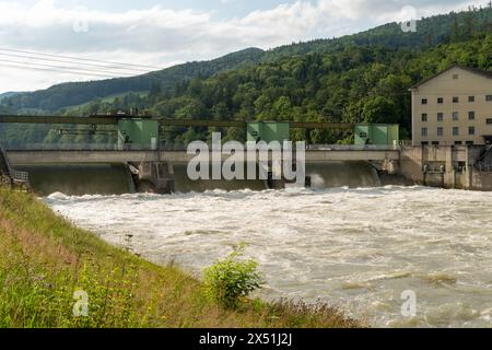 Wasserkraftwerk nach starkem Regen, mit schnell fließendem Wasser über das Wehr. Stockfoto