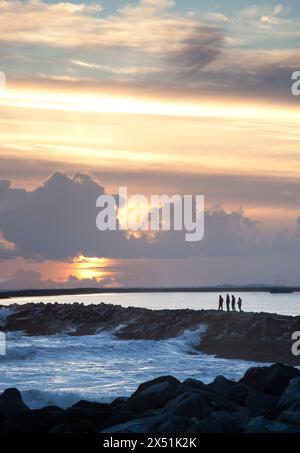 Eine Gruppe von Leuten beobachtet den Sonnenuntergang von einem Steg außerhalb von Half Moon Bay, CA. Stockfoto