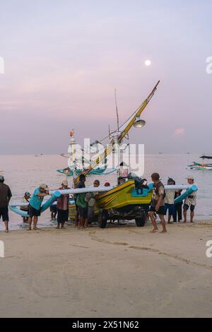 Fischer Rollen ein Fischerboot vom Wasser zum Ufer. Stockfoto