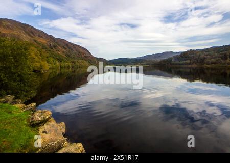 Ein fast perfektes Spiegelbild des blauen Himmels und der gefiederten Wolken im ruhigen Wasser des Bergsees von Llyn Dinas im Eryri-Nationalpark in Wales Stockfoto