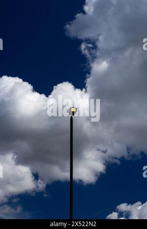 LED-Leuchten leuchten tagsüber mit dramatischem blauem Himmel und weißen Wolken. Hohe Lampenständer stehen sowohl im hoch- als auch im Querformat aufrecht. Platz zum Kopieren Stockfoto