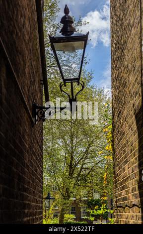 Eine geheime Gasse im wunderschönen Highgate Village London. Eine enge Gasse zwischen der High Street und dem Pond Square an einem sonnigen Tag mit alter Beleuchtungsausrüstung Stockfoto