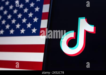 Vancouver, KANADA - April 30 2024 : TikTok-Logo auf einem iPhone-Bildschirm auf amerikanischem Flaggenhintergrund Stockfoto
