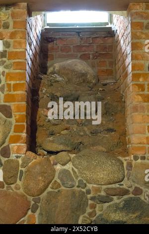 Ein rätselhaftes Fenster in den unterirdischen Kammern eines alten Schlosses, eingerahmt von Stein- und Ziegelmauern, die ein eindringliches Ambiente schaffen, das perfekt für Historis ist Stockfoto