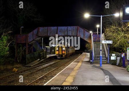 Ein Zug der Northern Rail-Klasse 158 158754 am Bahnhof Clapham, Yorkshire, auf der kleinen Nordwestlinie bei Nacht mit der Bahnhofsbrücke Stockfoto