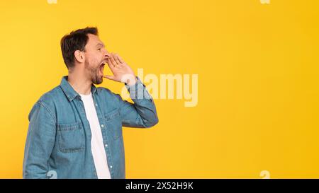 Mann steht vor der gelben Mauer und schreiend Stockfoto