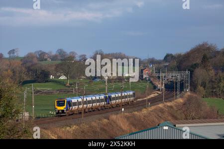 2 Dieseltriebwagen der Northern Rail Class 195 CAF 195124 + 195123 auf der elektrifizierten Hauptstrecke der Westküste in Lancashire durch die Landschaft Stockfoto