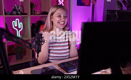 Eine fröhliche Frau strömt aus einem pulsierenden Spielzimmer, beleuchtet von mehrfarbigen LED-Lichtern bei Nacht. Stockfoto