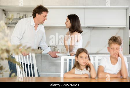 Eltern streiten sich hinter dem Rücken von verschwommenem, unerkennbarem Sohn und Tochter. Stockfoto