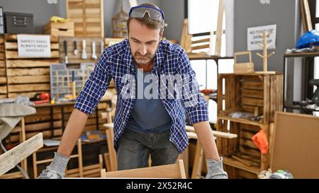 Ein hispanischer Mann mittleren Alters mit Bart arbeitet aufmerksam in einer Tischlerei und verkörpert handwerkliches Können. Stockfoto