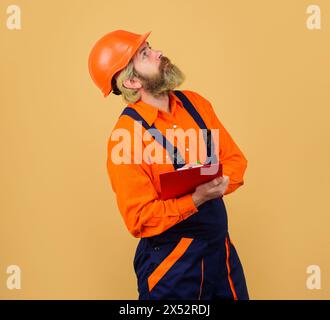 Baumeister, Ingenieur oder Architekt in Uniform und Schutzhelm mit Klemmbrett. Inspektionsberatung. Inspektor überprüft Material an der Konstruktion Stockfoto