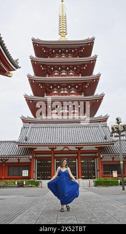 Die sprudelnde hispanische Frau tanzt fröhlich und dreht sich in wunderschönem Kleid inmitten der herrlichen Architektur des Senso-JI-Tempels in tokio. Sie ist durch japan gereist Stockfoto