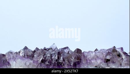 Schöne Drone aus natürlichem violettem Mineralamethysten auf weißem Hintergrund. Banner mit großen Amethyst-Kristallen. Kopierbereich. Stockfoto