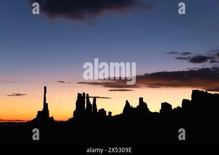 Sonnenaufgang hinter dem berühmten Totempfahl des Monument Valley und den nahegelegenen Türmen, die alle durch Millionen von Jahren Erosion durch Wind und Regen entstanden sind. Stockfoto