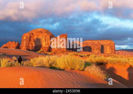 Die von der aufgehenden Sonne beleuchtete Berglandschaft wirft eine orange Farbe auf die Landschaft im Monument Valley, Arizona, ein Reiseziel für Abenteuer im Südwesten Stockfoto