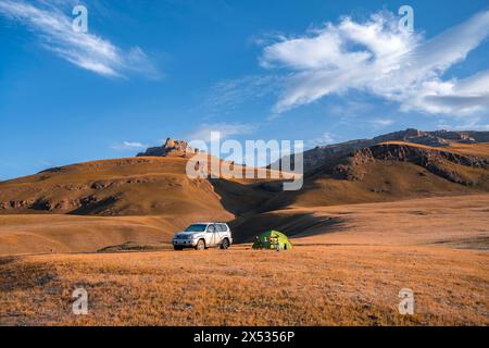 Geländefahrzeug Toyota Land Cruiser und grünes Campingzelt im kirgisischen Hochland, Hügel mit gelbem Gras, Sary Jaz Tal, Tien Shan, Kirgisista Stockfoto
