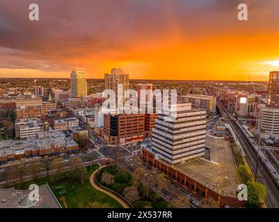 Blick auf die Innenstadt von New Brunswick in New Jersey mit Büro- und Wohngebäude und farbenfrohem orangefarbenem Himmel aus der Vogelperspektive Stockfoto