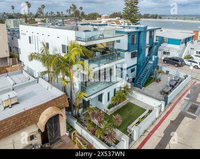 Blick aus der Vogelperspektive auf blau-weiße, moderne mehrstöckige Strandhäuser am Mission Beach mit großer Terrasse, Dachterrasse und Treppen, die zu den oberen Etagen führen Stockfoto