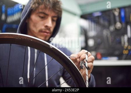 Hispanischer Mann, der an einem Fahrradgemälde arbeitet. Zeit zum Entfernen des Abdeckbands der Radfelge. Stockfoto