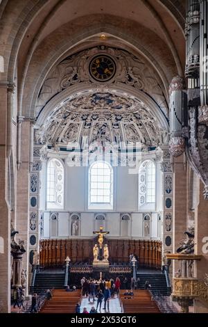 Trier, Rijnland-Palts, Deutschland, 23. März 2024, die Apsis des Trierer Doms ist prächtig erfasst, mit einem kunstvollen Altar, an dem sich Gläubige versammeln. Darüber befindet sich eine barocke Uhr als zeitloser Wächter inmitten einer beeindruckenden Auswahl an Skulpturenreliefs. Das Kruzifix steht zentral, eine Verkörperung des spirituellen Kerns der Kathedrale, während die umliegenden architektonischen Elemente von jahrhundertelanger religiöser Kunst und Tradition sprechen. Kunstvoller Altar und Barockuhr der Trierer Domapse. Hochwertige Fotos Stockfoto