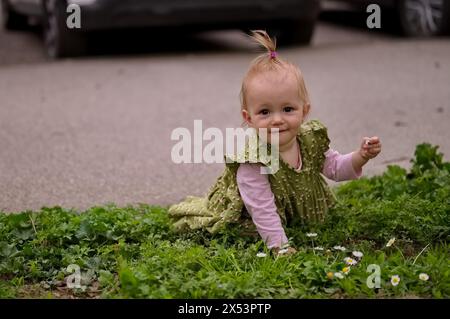 Ein kleines Mädchen hockt sich im Gras und pflückt Blumen Stockfoto