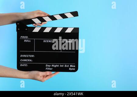 Frau mit Filmklatsch auf hellblauem Hintergrund, Nahaufnahme. Leerzeichen für Text Stockfoto