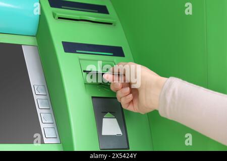 Frau, die Kreditkarte in den grünen Geldautomat steckt, Nahaufnahme Stockfoto