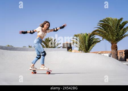 Eine junge Anfängerin surft auf einer Zementrampe und zeigt ihre Fähigkeiten und Leidenschaft für Skateboarden. Stockfoto