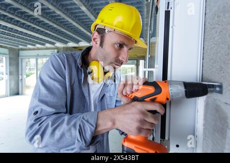 Ein Mann, der ein Loch in der Betonwand bohrt Stockfoto