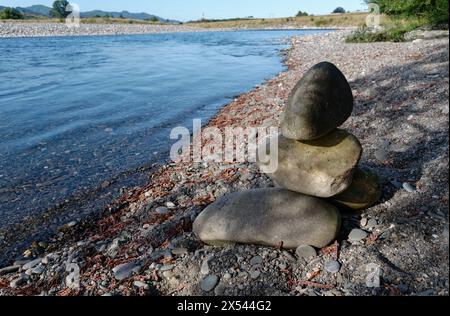 Einige große Steine stapeln sich übereinander auf einem steinernen Flussufer. Stockfoto