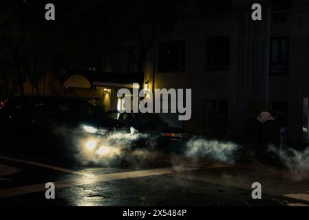 Autos mit ihren Scheinwerfern, die nachts in Steam-Modus verdeckt sind – Midtown Manhattan, New York City Stockfoto