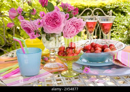 Botanik, rosafarbene Rosen im Glas auf einem Tisch mit Gläsern Rotwein und Kirschen in Schüsseln im Freien, ZUSÄTZLICHE RECHTE-CLEARANCE-INFO-NICHT-VERFÜGBAR Stockfoto