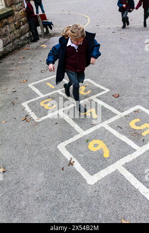 Grundschüler spielen hopfscotch auf einem Schulhof während ihrer Pause vom Unterricht. Stockfoto