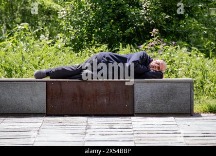 Älterer Vagrant, der auf Parkbank ruht Stockfoto