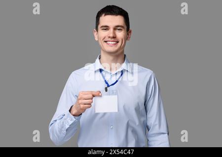 Lächelnder Mann mit leerem Abzeichen auf grauem Hintergrund Stockfoto