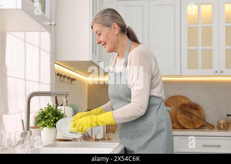 Glückliche Hausfrau Waschplatte in Küchenspüle Stockfoto