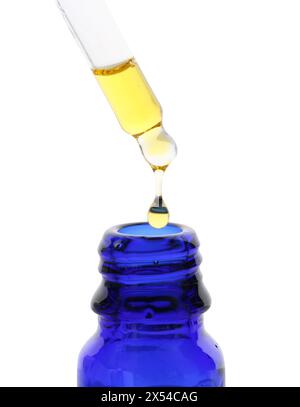 Tropfende Tinktur von der Pipette in die Flasche isoliert auf weiß Stockfoto